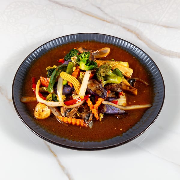 A dark plate of Phirom Thai Restaurant's stir-fried mixed vegetables in a rich brown sauce.