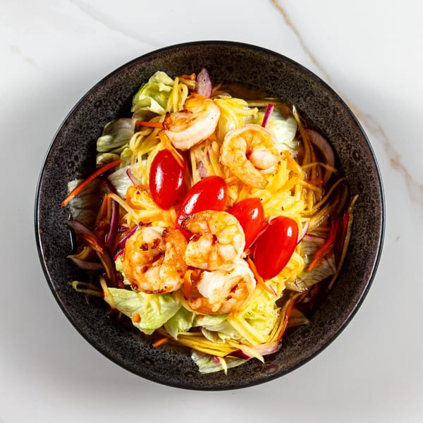Phirom Thai Restaurant's vibrant Thai salad with grilled shrimp, cherry tomatoes, and shredded mango.